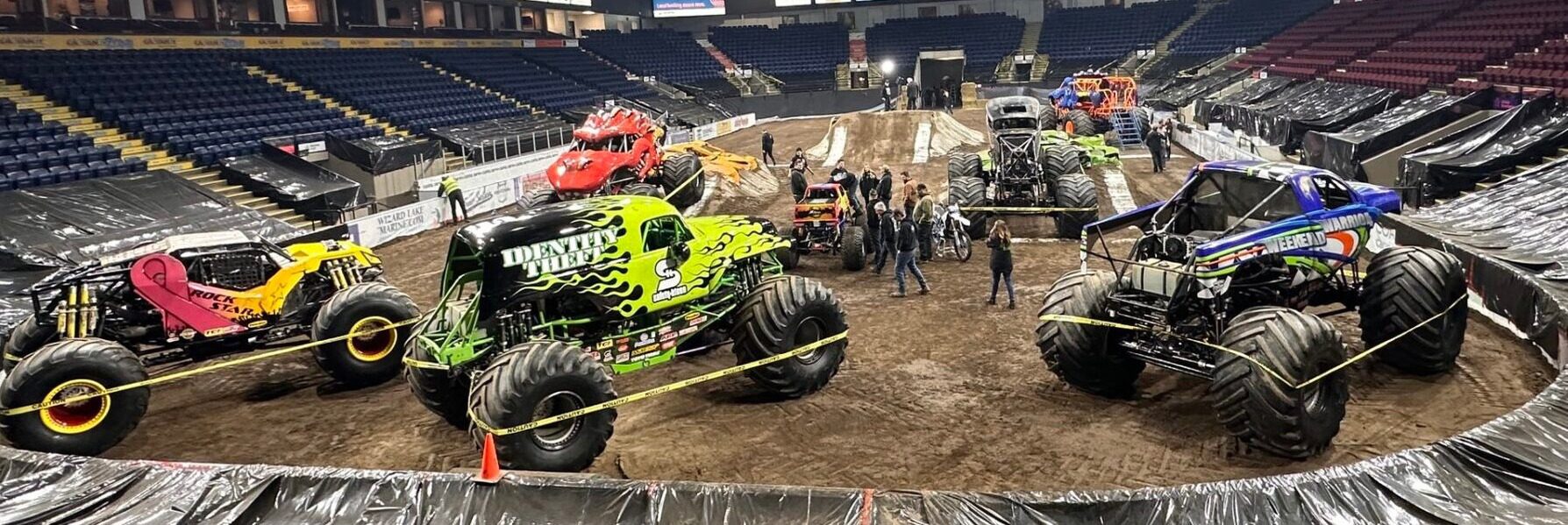 A thrilling scene in an arena featuring various monster trucks, showcasing their unique designs and powerful presence.