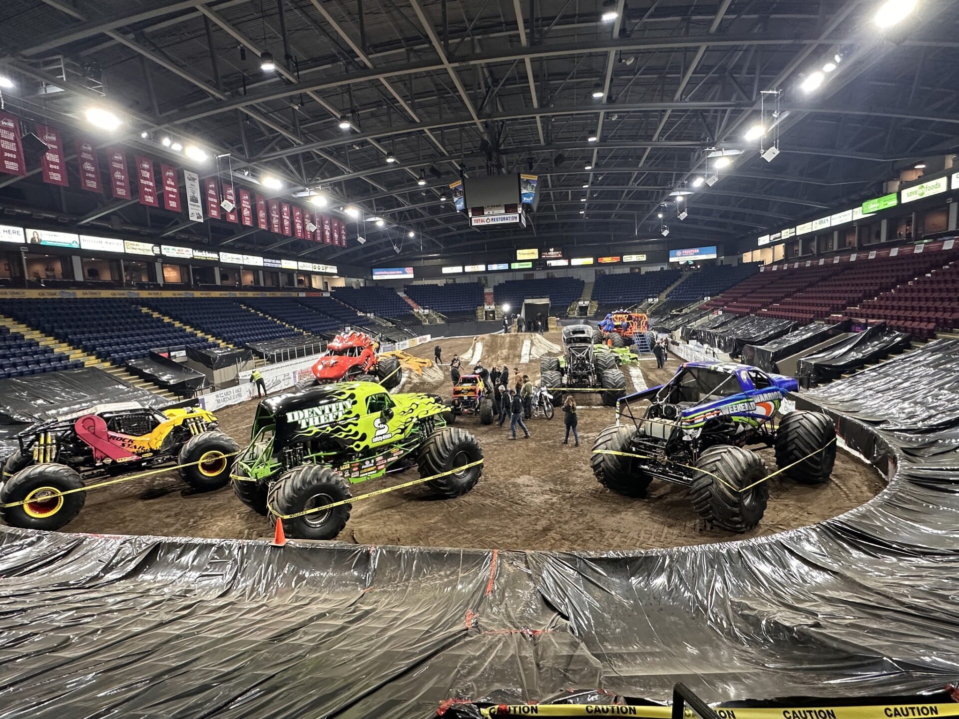 A thrilling scene in an arena featuring various monster trucks, showcasing their unique designs and powerful presence.